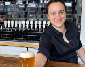 Person handing beer across bar.